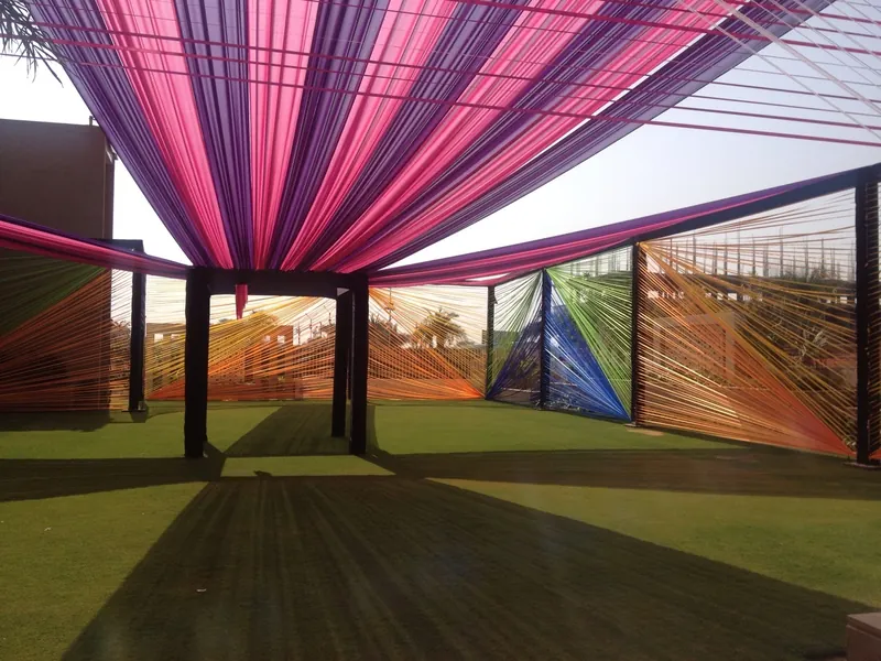 A magenta and pink fabric canopy radiating from a central column over a lawn