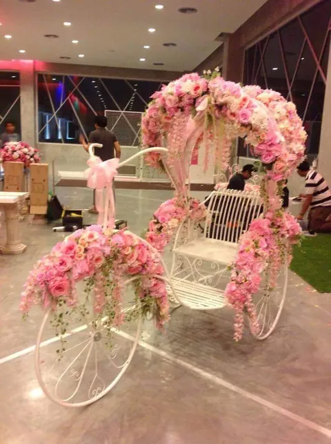 A pink floral carriage decorated with roses, framed by drapes