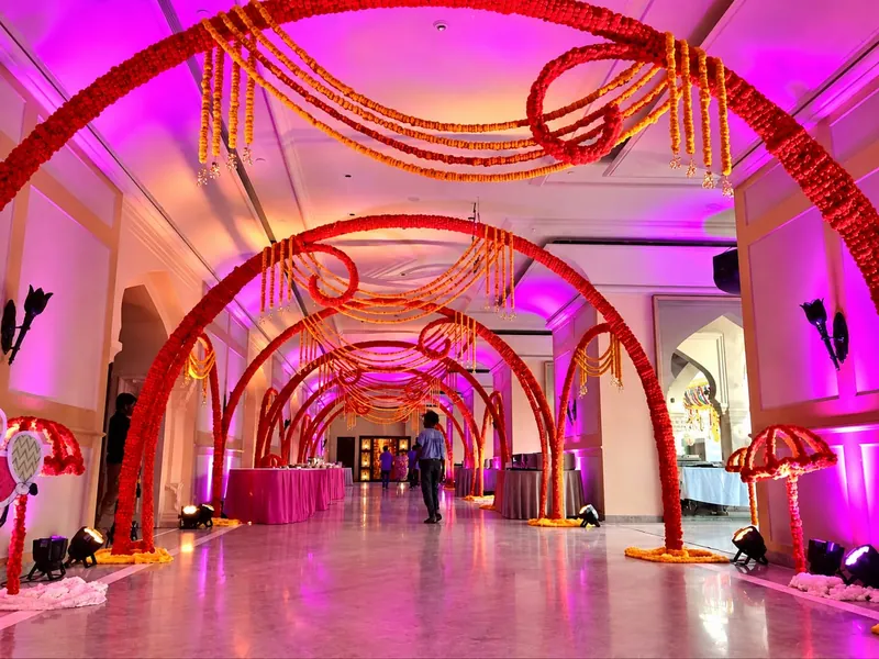 Red and gold marigold arch corridor with magenta uplighting, hanging garlands running the length of the walkway